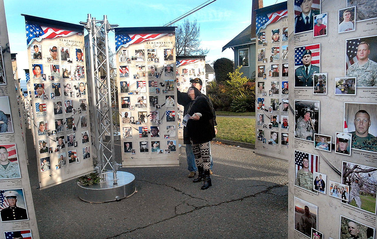 Jeff and Kathy Thayer of Port Angeles look through the photos of military personnel killed since Sept. 11, 2001 at the “Remembering Our Fallen ” traveling memorial on display through Monday in the 1100 block of South Oak Street in Port Angeles. (Keith Thorpe/Peninsula Daily News)