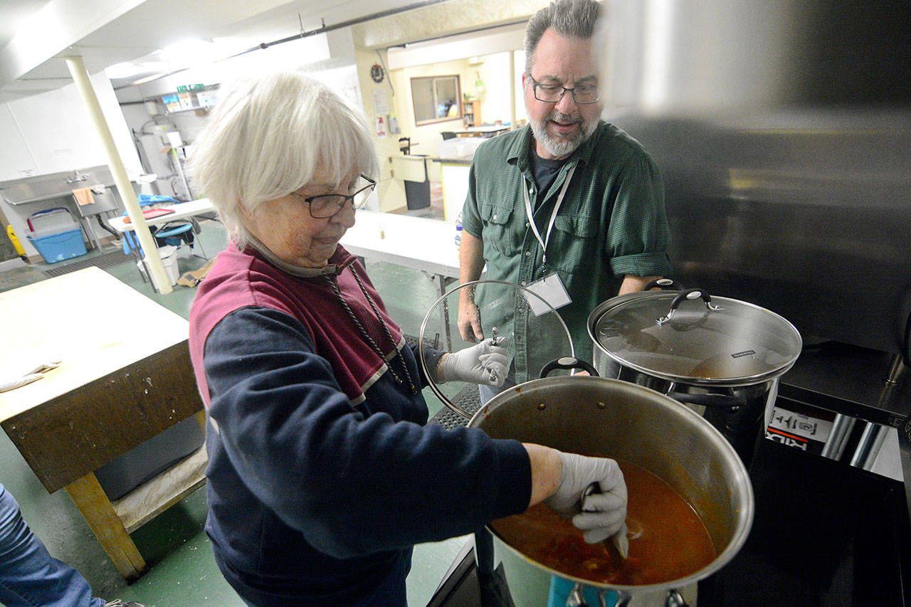 Sue Hagge and the Rev. Skip Cadorette of First Baptist Church of Port Townsend cook dinner at the Jefferson County Winter Shelter on Wednesday. (Jesse Major/Peninsula Daily News)