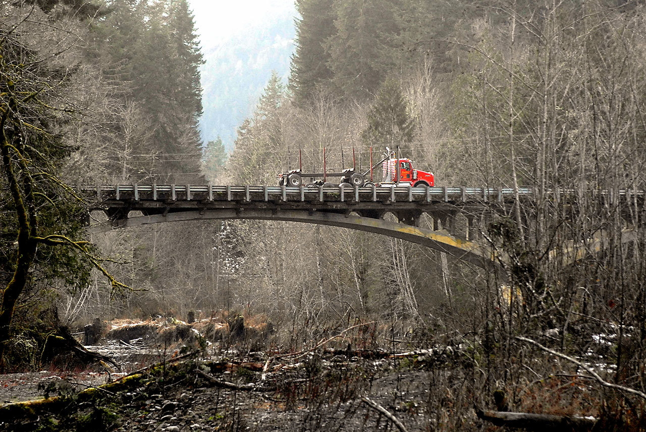A logging truck makes its way across the U.S. Highway 101 bridge over the Elwha River west of Port Angeles in December 2016. (Keith Thorpe/Peninsula Daily News)