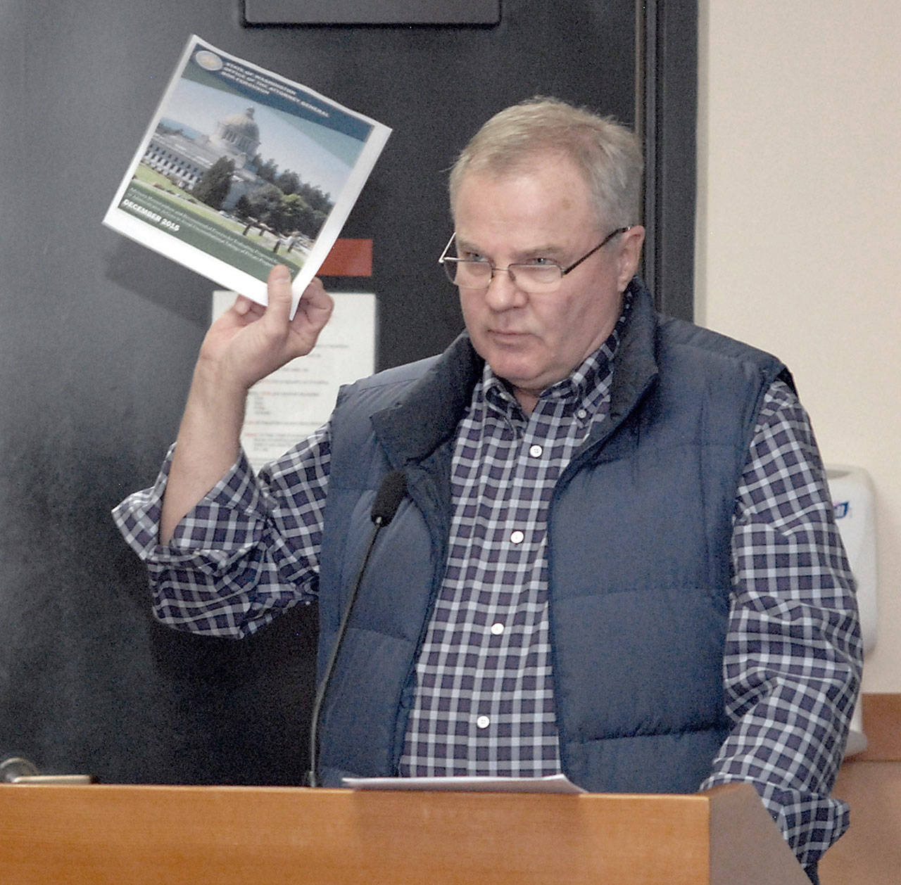 Port Angeles Business Association member Jim McEntire, a former commissioner for Clallam County and the Port of Port Angeles, holds up the front page of a state document on regulatory limits as he testifies during a public hearing Tuesday before the Clallam County Board of Commissioners. (Keith Thorpe/Peninsula Daily News)