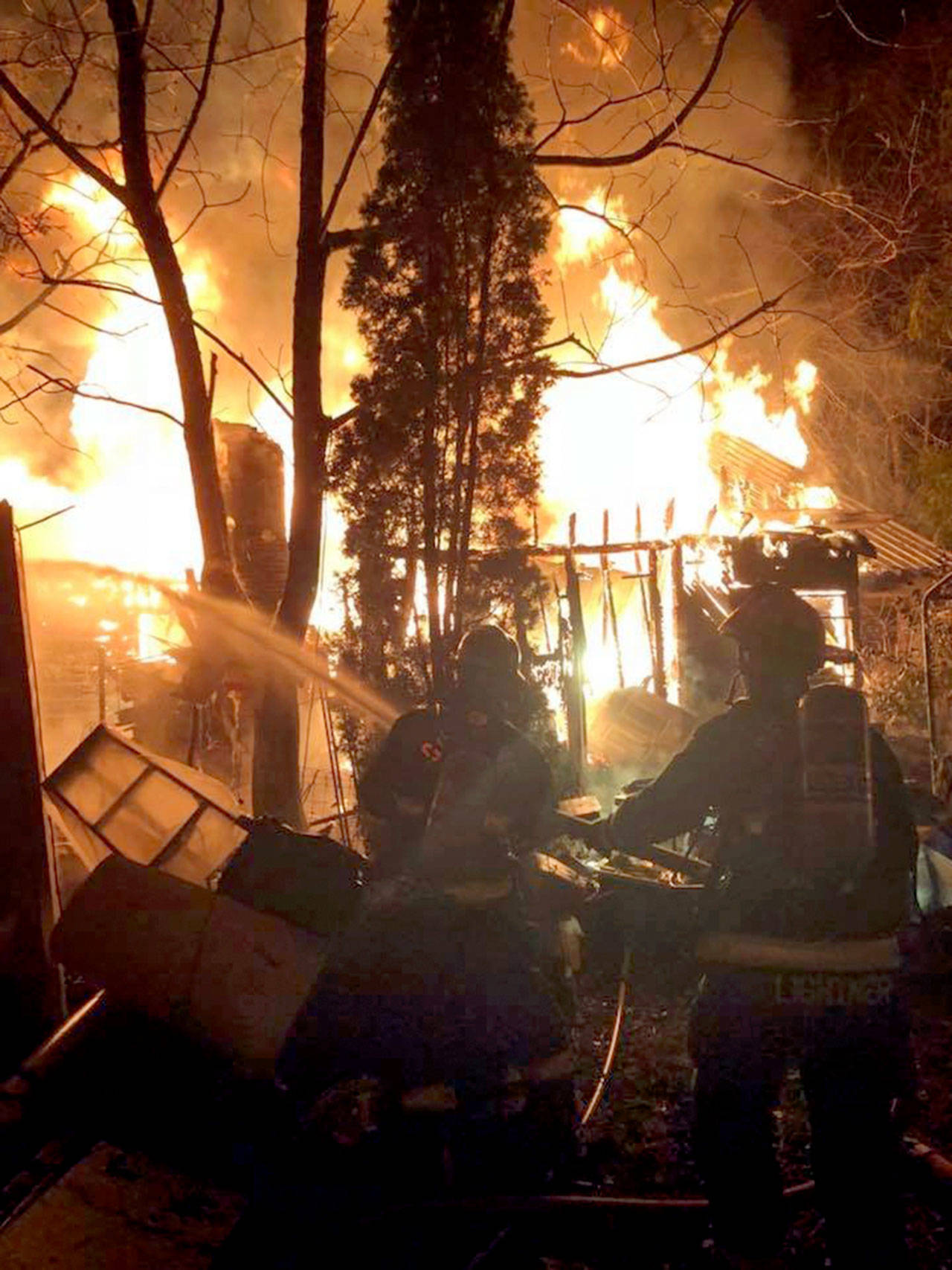 Firefighters fight a house fire in Brinnon that left a man homeless Monday and shut down U.S. Highway 101 for much of Monday night. (Denise Karp)