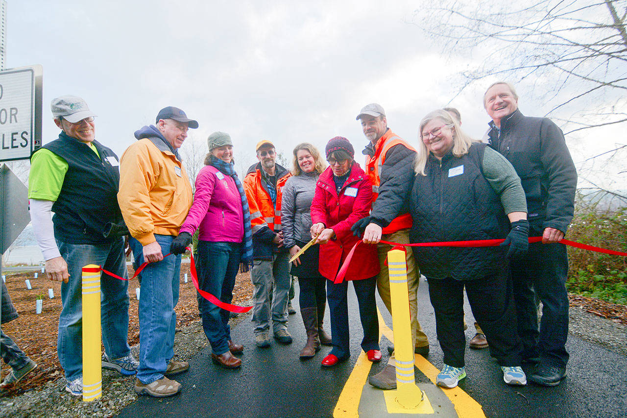 Jefferson County Commissioner Kathleen Kler cuts the ribbon during the opening celebration of a section of the Olympic Discovery Trail along South Discovery Bay on Friday. (Jesse Major/Peninsula Daily News)