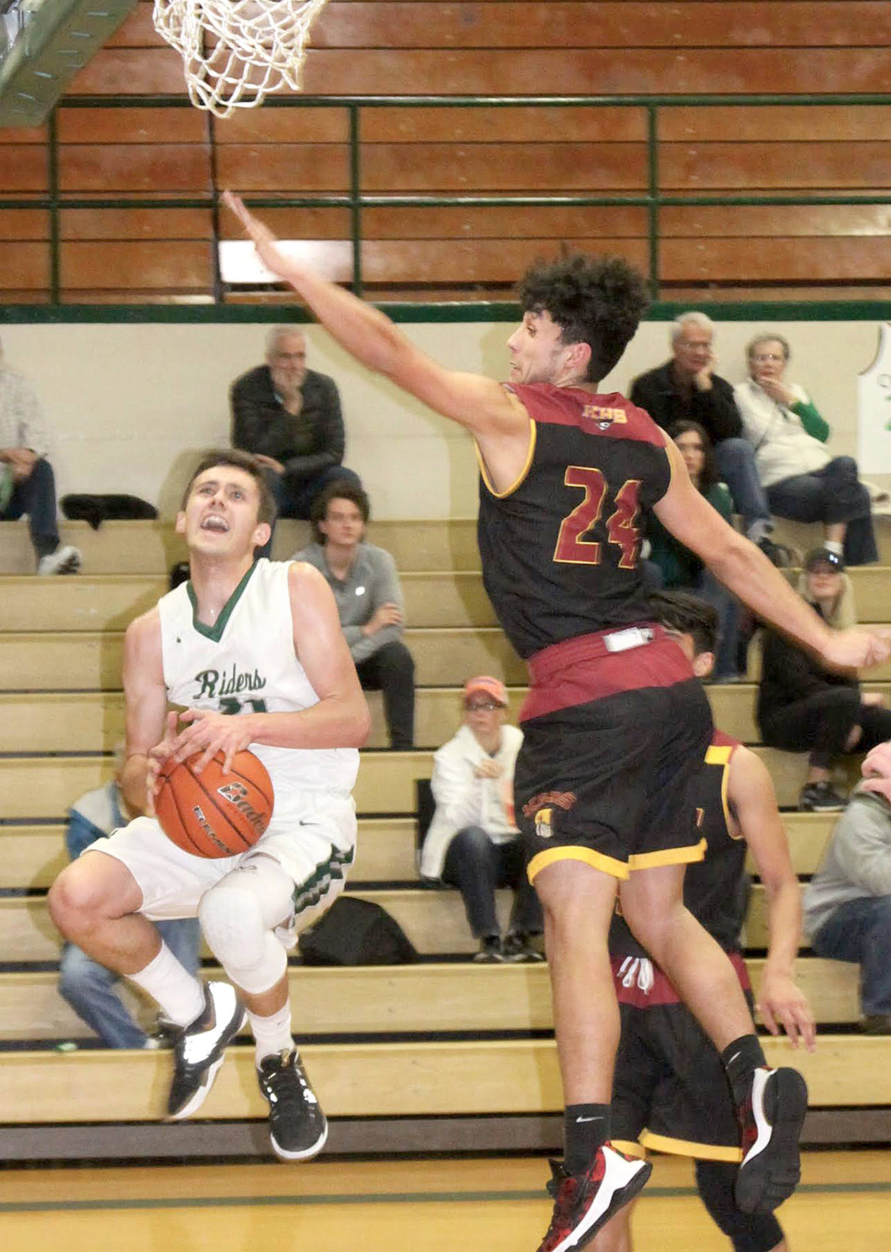 Dave Logan/for Peninsula Daily News Port Angeles’ Kyle Benedict, left, slips under the defense of Kingston’s Kynoa Sipai during the Roughriders’ 61-37 win over the Buccaneers at home Friday.
