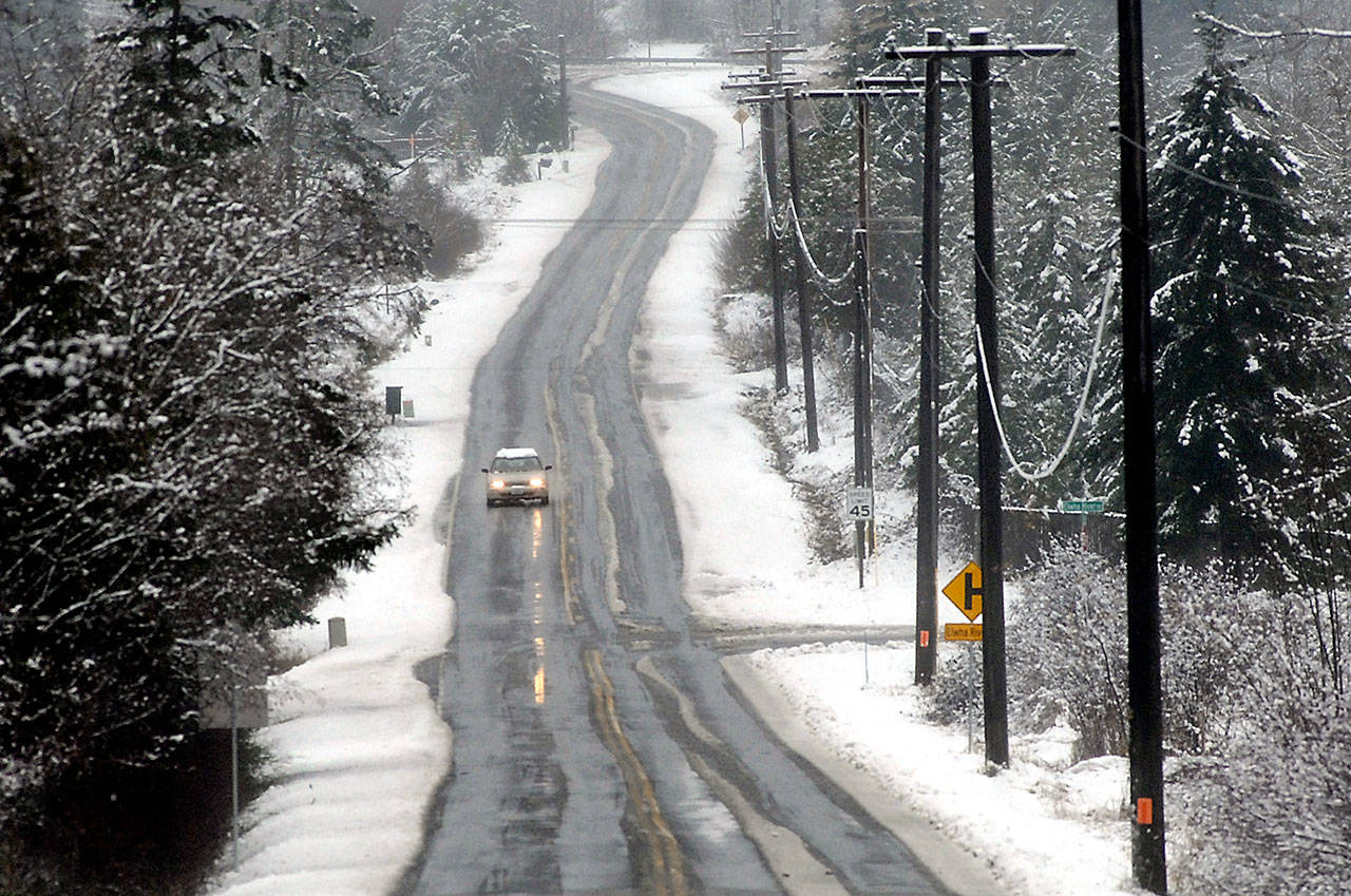 A car makes it way along a slushy section of Laird Road west of Port Angeles on Tuesday after a passing front left a layer of snow across portions of the North Olympic Peninsula. Cool, dry air is expected to settle in over the area for Wednesday and Thursday with another chance of snow showers Thursday night through Friday morning. (Keith Thorpe/Peninsula Daily News)