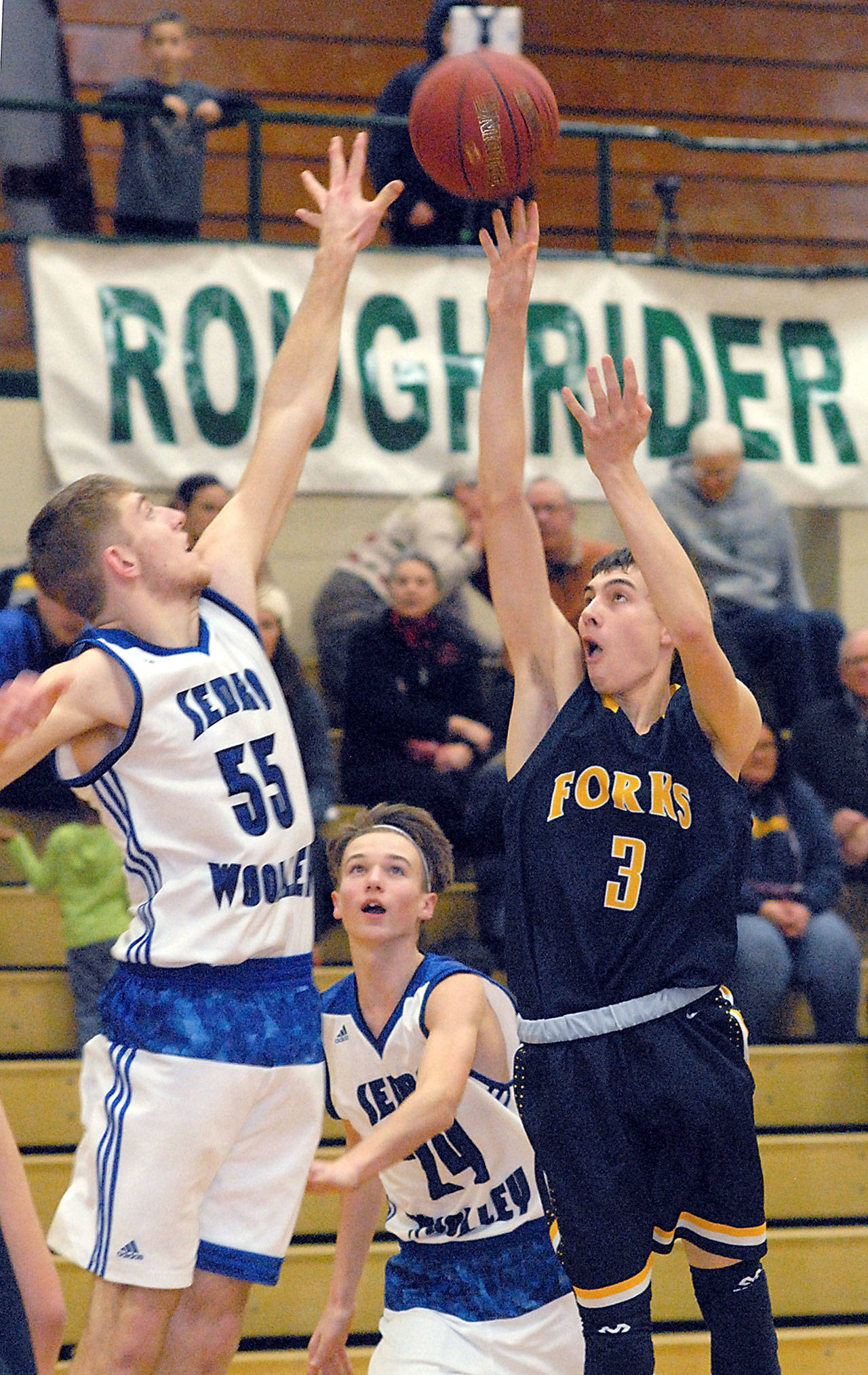 Keith Thorpe/Peninsula Daily News Forks’ Jake Jacoby, right, takes a shot as Sedro-Woolley’s Bryson Bartlett, left, and Keenan Hofstad defend during Friday night’s first round of the Port Angeles Holiday Basketball Tournament.