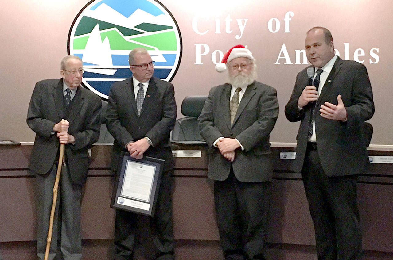 Mayor Patrick Downie, left, and fellow outgoing Port Angeles City Council members Dan Gase, Brad Collins and Lee Whetham (speaking) received proclamations in recognition of their public service Dec. 19. (Rob Ollikainen/Peninsula Daily News)