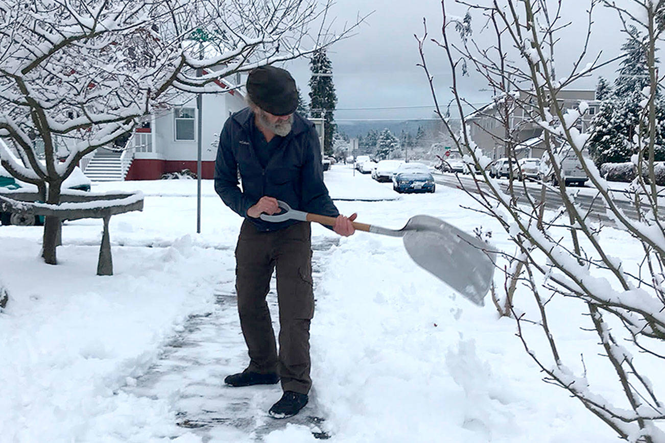 Paul Gottlieb/Peninsula Daily News Greg Shield shoveled snow Christmas morning from the sidewalk in front of his house at Cedar and West Seventh streets in Port Angeles. About 5 inches fell in the neighborhood.