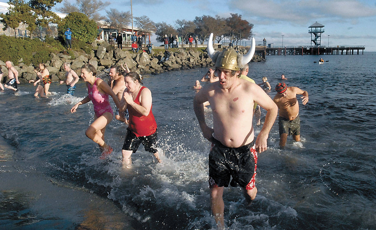 Chris Fowler of Port Angeles, wearing a viking hat, emerges from the chilly waters of Port Angeles Harbor with dozens of other people during the 2015 polar bear plunge in honor of the new year. (Keith Thorpe/Peninsula Daily News)