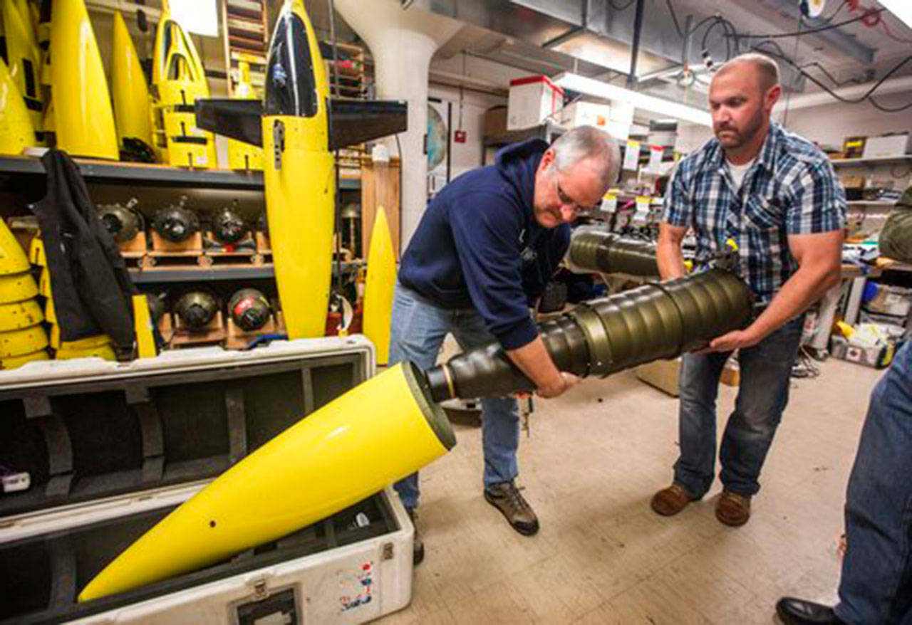 In a Nov. 20 photo, University of Washington oceanographers Jason Gobat and Ben Jokinen load the pupa into the underwater fairing sea glider that will be used in an antarctic expedition to gather data under the sea ice sheets to estimate future melting and sea level rise. (Steve Ringman/The Seattle Times via AP)