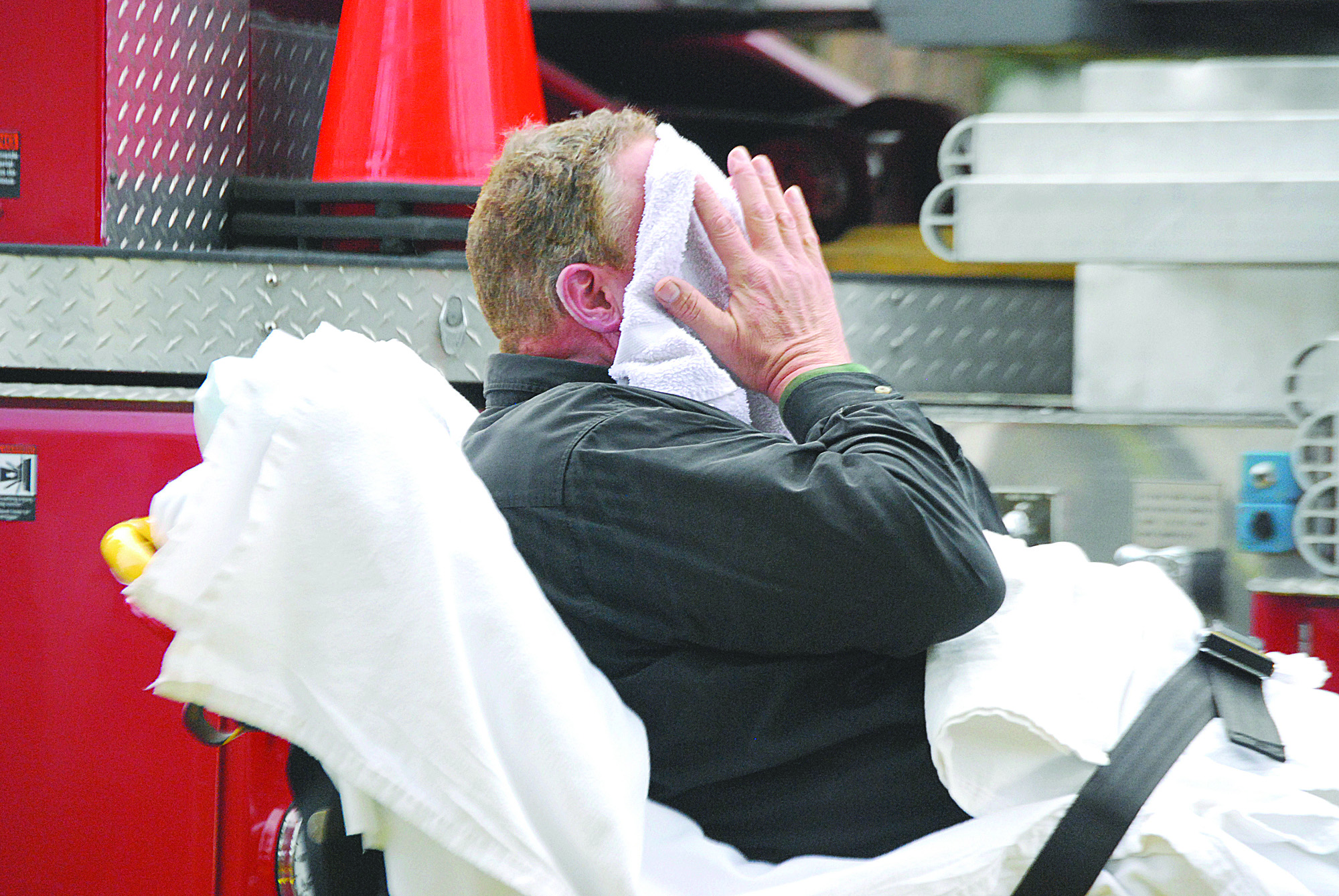 The unidentified heating company worker holds a wet towel to his face after receiving minor burns. He was taken to Olympic Medical Center in Port Angeles. Photo by Jeff Chew/Peninsula Daily News. Jeff Chew/Peninsula Daily News