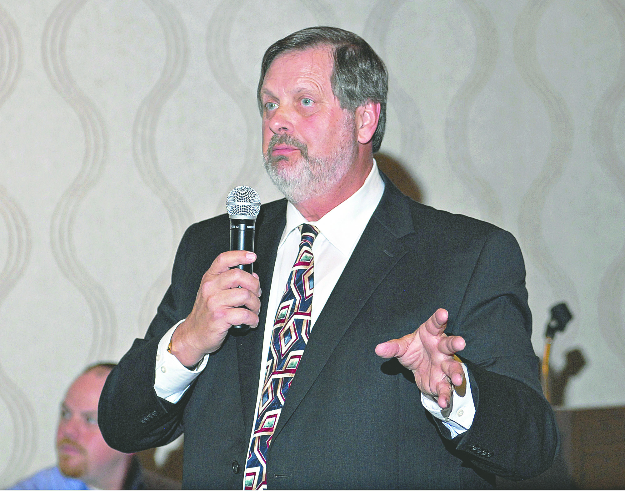 Peninsula College interim President Brinton Sprague speaks at the Port Angeles Regional Chamber of Commerce meeting on Monday. Seated at left is chamber President Brian Kuh. Chris Tucker/Peninsula Daily News