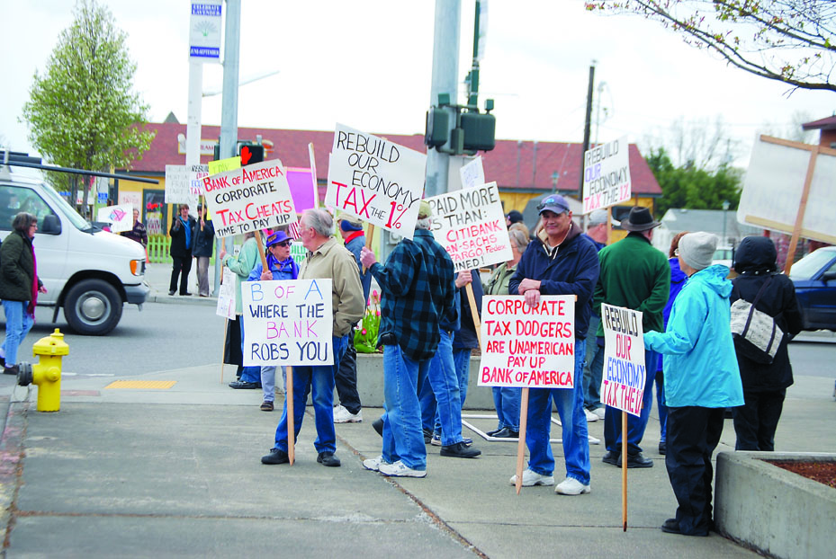 More than 30 MoveOn.org supporters from Sequim and Port Angeles gather at the intersection of Washington Street and Sequim Avenue late Tuesday afternoon for a “Tax Day” protest. The message of the group led by Andrea Radich of Port Angeles — to tax the 1 percent and spare the 99 percent — echoed similar protests across the nation. Jeff Chew/Peninsula Daily News