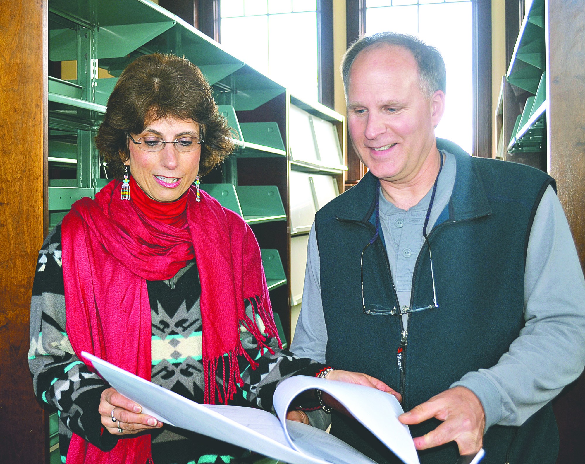 Port Townsend Library Director Theresa Percy and project manager city Michael Hoskins examine the plans for the Carnegie Library in front of its empty shelves. The seismic retrofit is about to begin on the building. Charlie Bermant/Peninsula Daily News