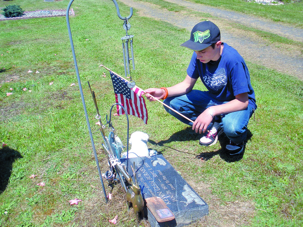 Quilcene eighth-grader Trevor Burnston decorates the marker of his uncle