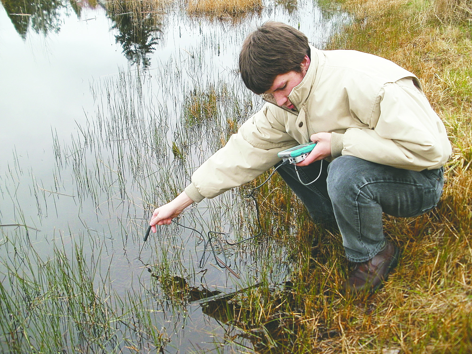 Port Townsend High School sophomore Ewan Shortess takes water temperature readings for his research project on the health of the Froggy Bottoms wetland. Jennifer Jackson/for Peninsula Daily News