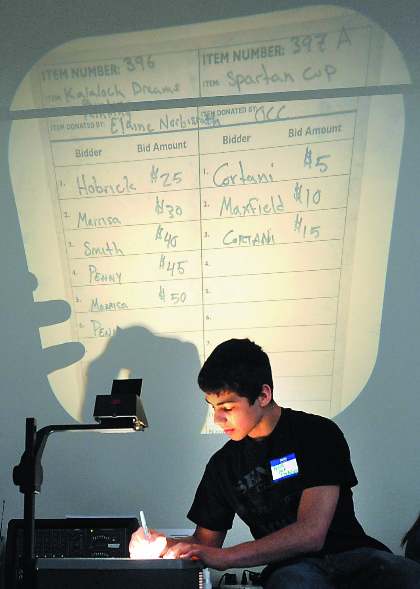 2011 Forks High School graduate Tyler Cortani enters bids on the overhead last year during the Quillayute Valley School District auction at the Bank of America building in Forks. This year's auction will take place at the Forks High School gym. Lonnie Archibald/for Peninsula Daily News