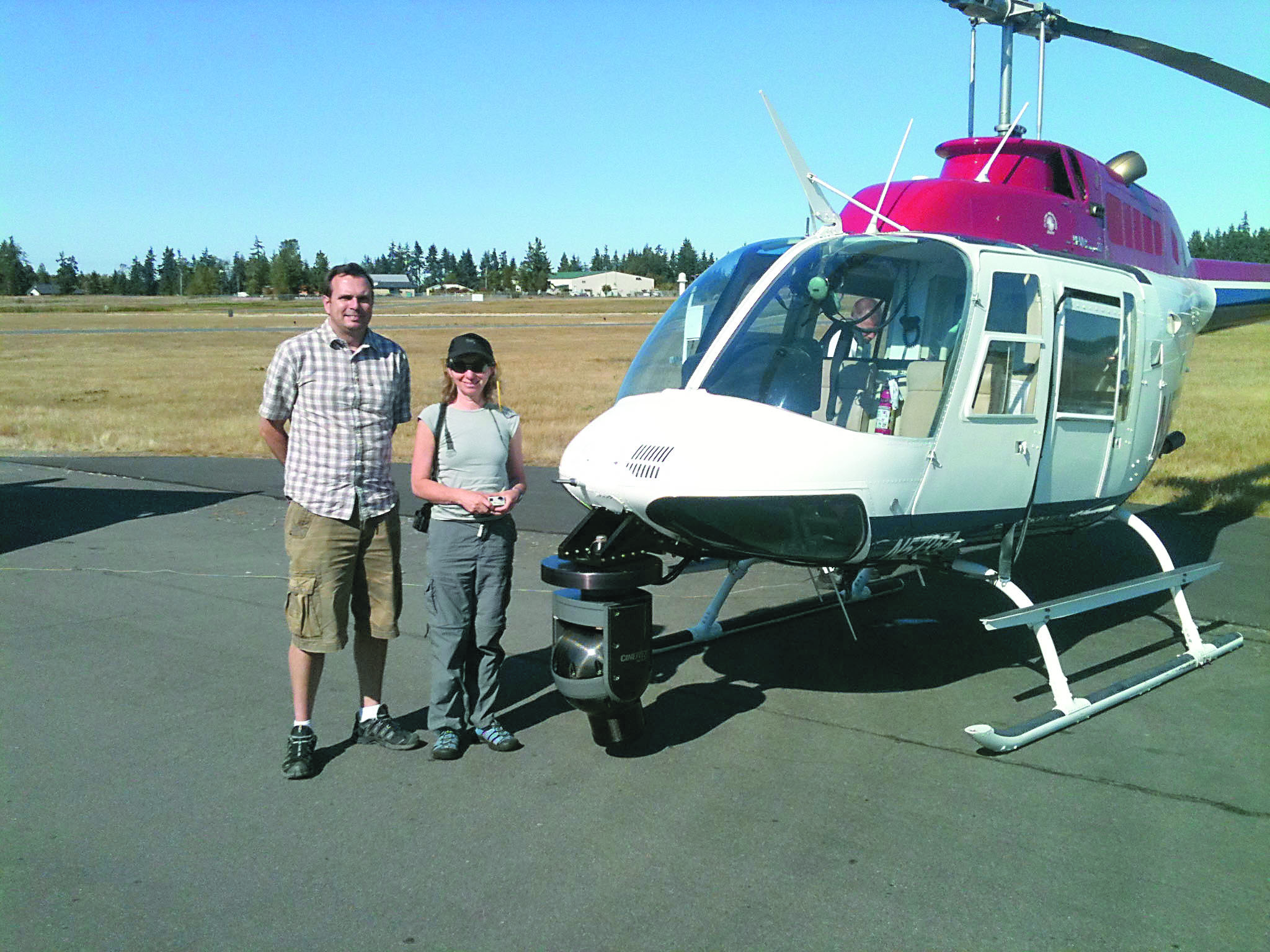 Filmmakers John Trapman and Shelly Solomon pause beside the helicopter that took them high above the Elwha River as they made their movie.