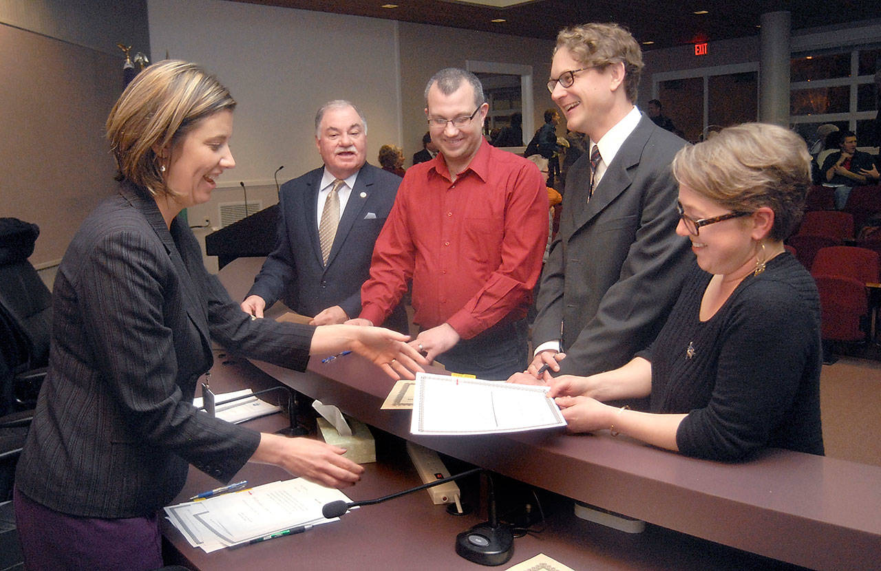 Port Angeles City Clerk Jennifer Veneklasen, left, collects signed paperwork from new City Council members, from center left, Jim Moran, Mike French, Lindsey Schromen-Wawrin and Kate Dexter after the four were sworn in to their positions during a special ceremony Tuesday at Port Angeles City Hall. The new members later joined incumbents Cherie Kidd, Sissi Bruch and Michael Merideth for the first council meeting of 2018. (Keith Thorpe/Peninsula Daily News)