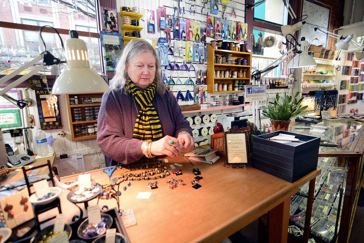 Lois Venarchick, who heads the Port Townsend Merchants Association and owns Wynwoods Gallery & Bead Studio, prices jewelry as she waits for customers to walk through her shop’s doors. (Jesse Major/Peninsula Daily News)