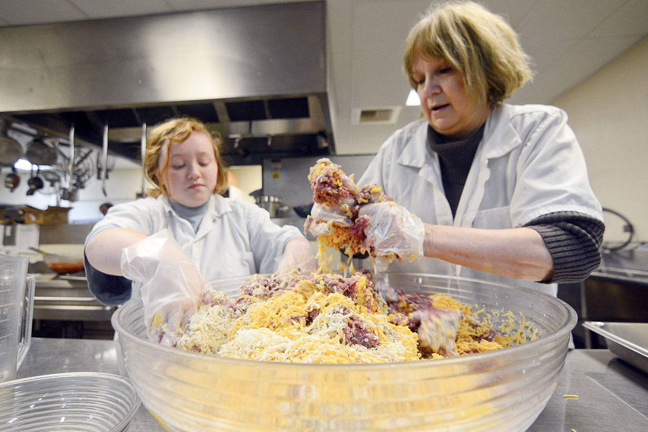 Ninth-grade student Alexis Mayson works with her teacher, Veda Wilson, to make meatloaf for Quilcene School on Thursday. (Jesse Major/Peninsula Daily News)