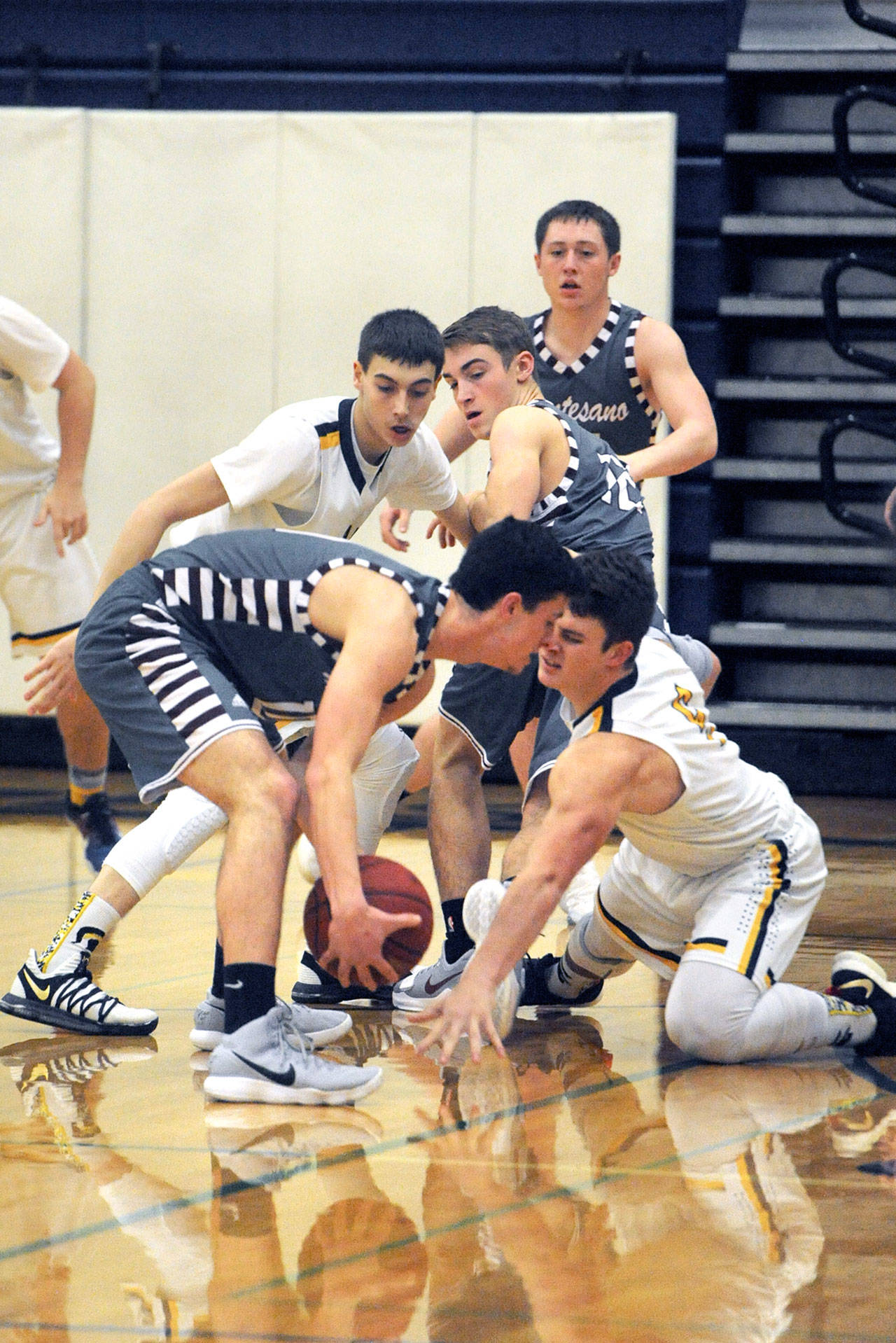 Lonnie Archibald/for Peninsula Daily News Forks’                                Jake Jacoby (left) and Cole Baysinger (on floor) go for the steal against Montesano’s Trevor Ridgway. Forks defeated Montesano 49 to 46 in a thriller to take over first place in the Evergreen League.