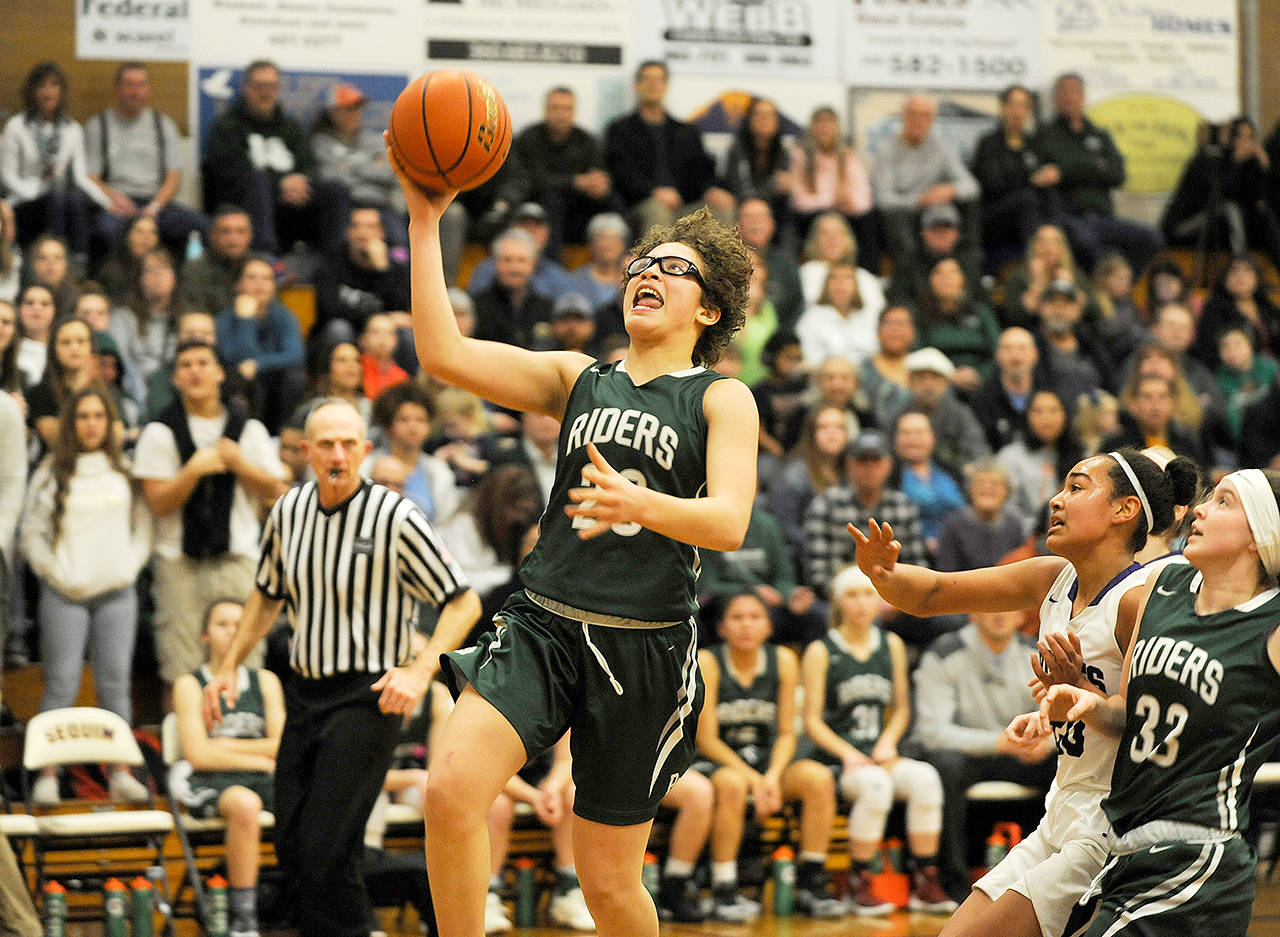 Port Angeles’ Madison Cooke rises for a layup while Sequim’s Jayla Julmist and Port Angeles’ Jaida Wood trail the play. Cooke scored a game-high 19 points to lead the Riders to a 60-33 rivalry win.                                Michael Dashiell/Olympic Peninsula News Group