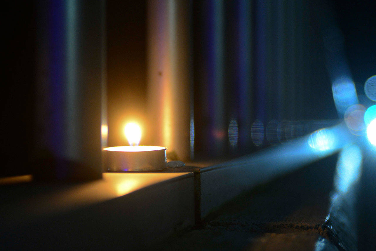 A candle flickers along the rail of the Valley Creek Eighth Street bridge in Port Angeles on Wednesday. (Jesse Major/Peninsula Daily News)
