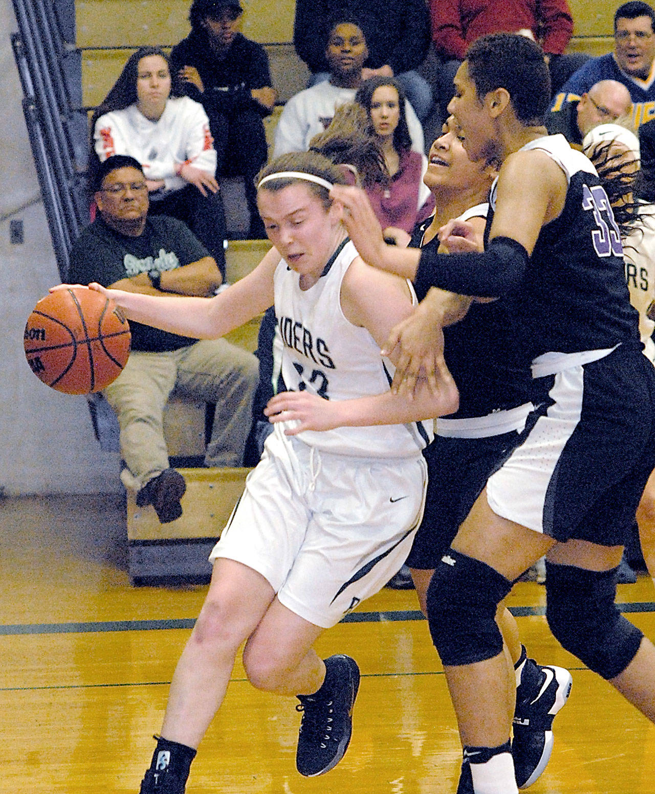 Port Angeles Jaida Wood, left drives along the baseline past Foster defenders Moeshana Maiava and Emolani Morris, right, in the second quarter of Friday nights playoff game at Port Angeles High School.                                Keith Thorpe/Peninsula Daily News