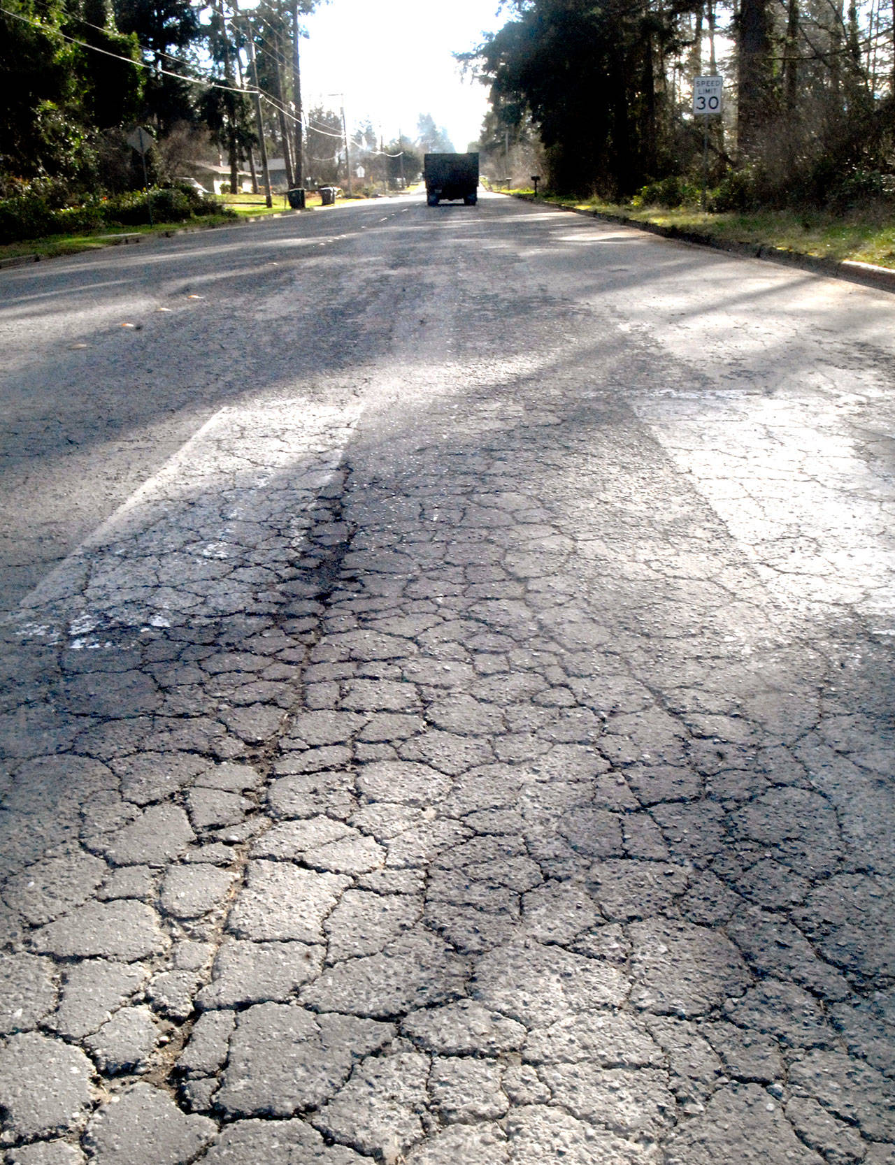 A cracked road surface greets motorists on West 10th Street in Port Angeles. The street is being considered for resurfacing by the city. (Keith Thorpe/Peninsula Daily News)