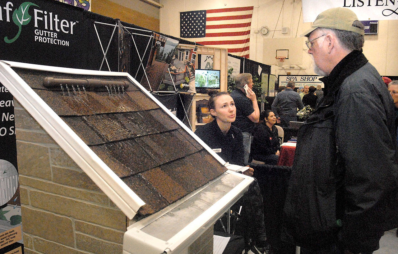 Ron Coffman of Port Angeles, right, talks with Jaydn Conrad of LeafFilter Gutter Protection about rain gutters during the 20th annual Building, Remodeling & Energy Expo in February 2017 at Sequim High School. (Keith Thorpe/Peninsula Daily News)