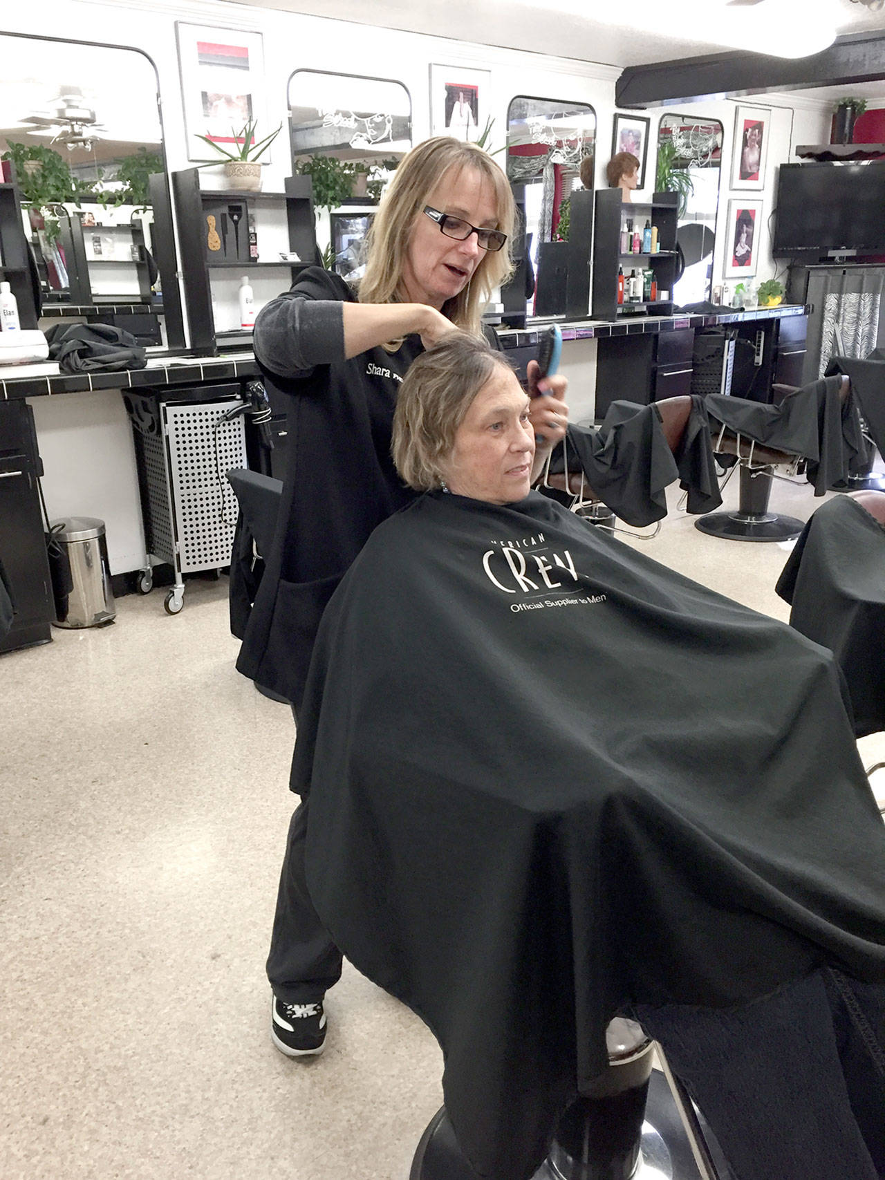 Shara Smith, owner of The Hair School in Port Angeles, talks with Dawn Saiz about the type of wig she’d like as part of an Olympic Medical Center and American Cancer Society program providing free wigs to women undergoing cancer treatment. (Fran Howell/for Peninsula Daily News)