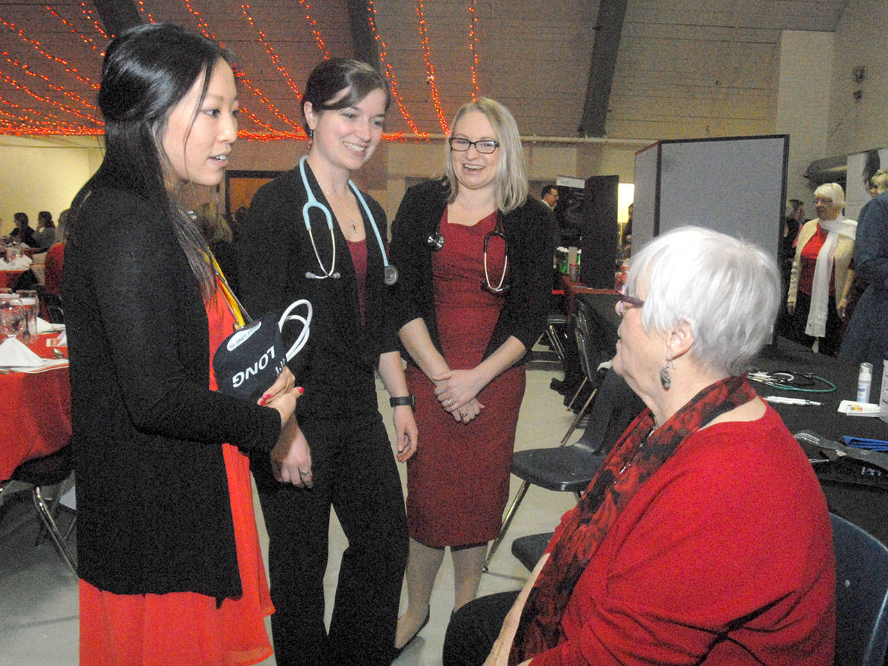 Olympic Medical Center workers, from left, exercise specialist Sherry Xiong, nuclear medical technician Brittany Payseno and cardiac sonographer Kerie Swegle talk with guest Dee Kurtz before the start of Friday’s 11th annual Red, Set, Go! Heart Luncheon at Vern Burton Community Center in Port Angeles. The charity event, hosted by the Jamestown S’Klallam Tribe, benefitted the Olympic Medical Center Foundation with the goal of raising funds toward the purchase of a nuclear camera for cardiac stress testing. (Keith Thorpe/Peninsula Daily News)