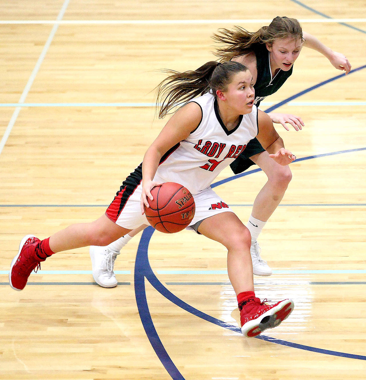 Neah Bay’ s Gina McCauley drives past Selkirk’s Bree Dawson in Neah Bay’s 52-43 1B Regionals victory Saturday. (David Willoughby/for Peninsula Daily News)