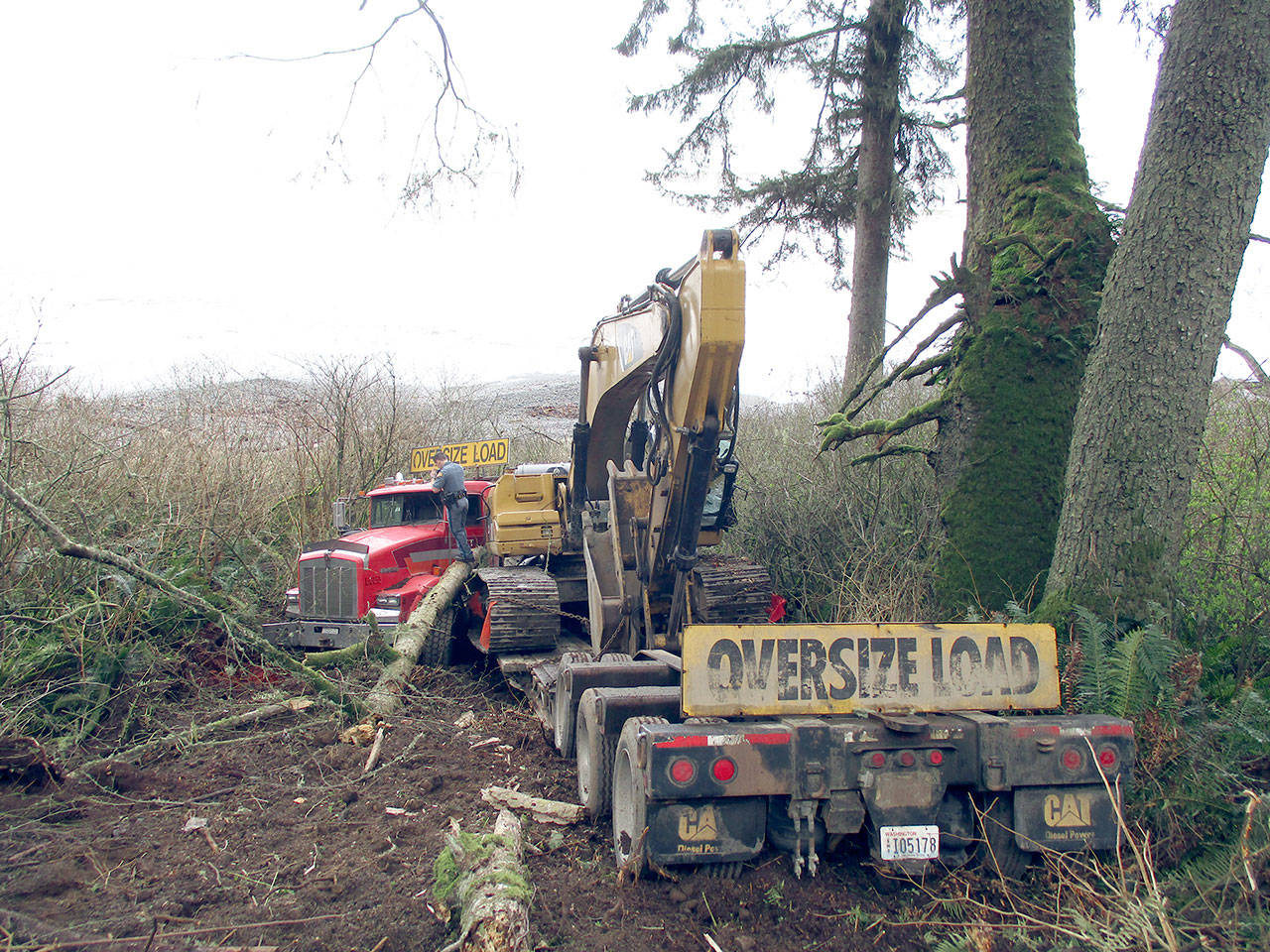 A truck hauling an excavator missed a turn at milepost 39 on state Highway 112 at 1 p.m. Monday, fell 100 feet down an embankment and jack-knifed on the beach below, according to State Patrol. (Kaleb Miller/Washington State Patrol)