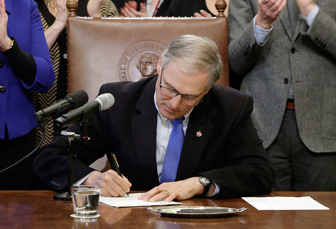 Gov. Jay Inslee signs a bill in Olympia that makes Washington the first state to set up its own net-neutrality requirements in response to the Federal Communications Commission’s recent repeal of Obama-era rules. (Ted S. Warren/The Associated Press)