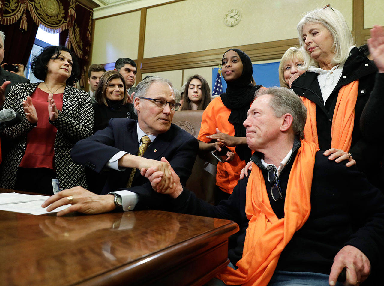 Gov. Jay Inslee, center, shakes hands with Jim Parsons, lower right, of Bainbridge Island as Parsons’ wife, Ann-Marie, upper right, looks on, Tuesday after Inslee signed a measure into law that bans the sale and possession of bump stocks. The Parsons’ daughter Carrie was one of the victims of a mass shooting at a country music concert in Las Vegas in 2017. (Ted S. Warren/The Associated Press)