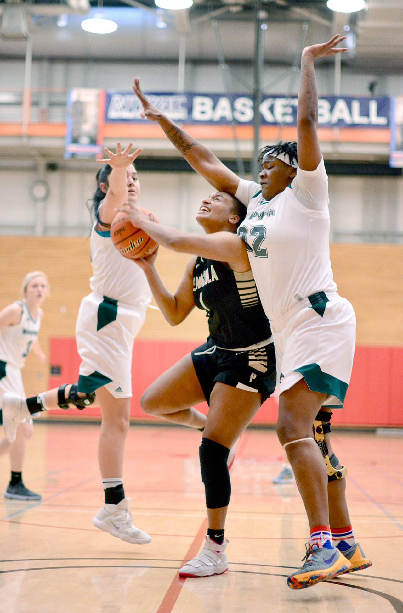 Peninsula’s Jamellia Clark, center, is defended by Umpqua’s Merrily Jones, left, and Dajanay Powell, during the Pirates’ 83-62 loss to Umpqua at the NWAC Women’s Basketball Championships at Everett Community College on Thursday. Jay Cline
