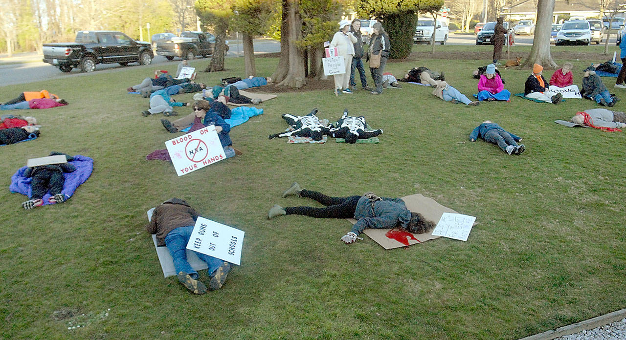 Anti-gun violence protesters simulate people killed by firearms on the east lawn of Vern Burton Community Center in Port Angeles on Saturday. (Keith Thorpe/Peninsula Daily News)