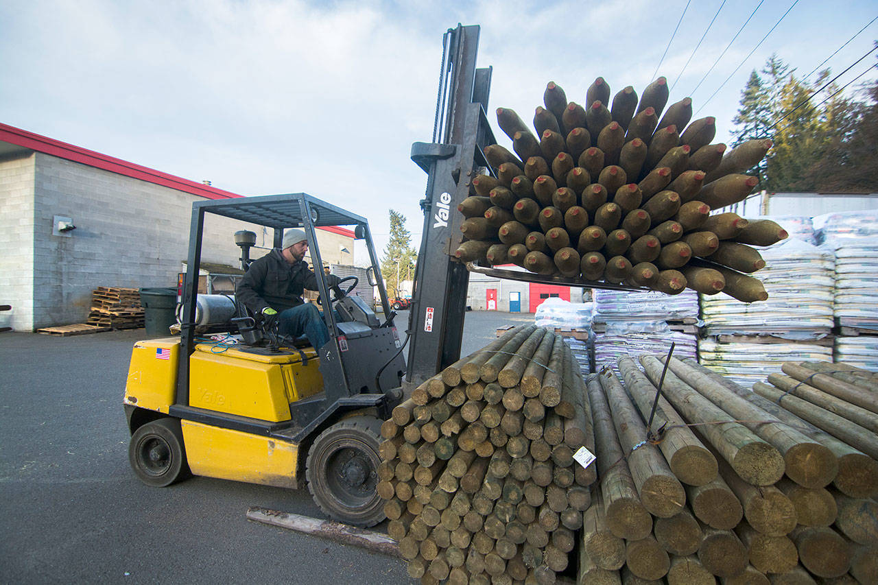 Lucas Dailey, warehouse worker at Leitz Farms in Port Angeles, uses a forklift to stack posts at the store Monday. (Jesse Major/Peninsula Daily News)