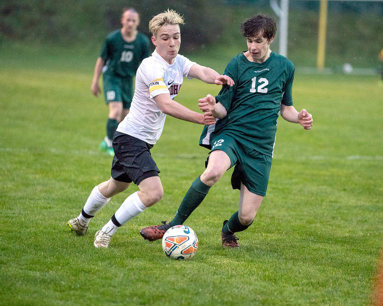 Port Angeles’ Andrew Methner, (12) and Redhawk Ian Kjeldgaard battle for the ball during a rainy match Tuesday at Memorial Field in Port Townsend.