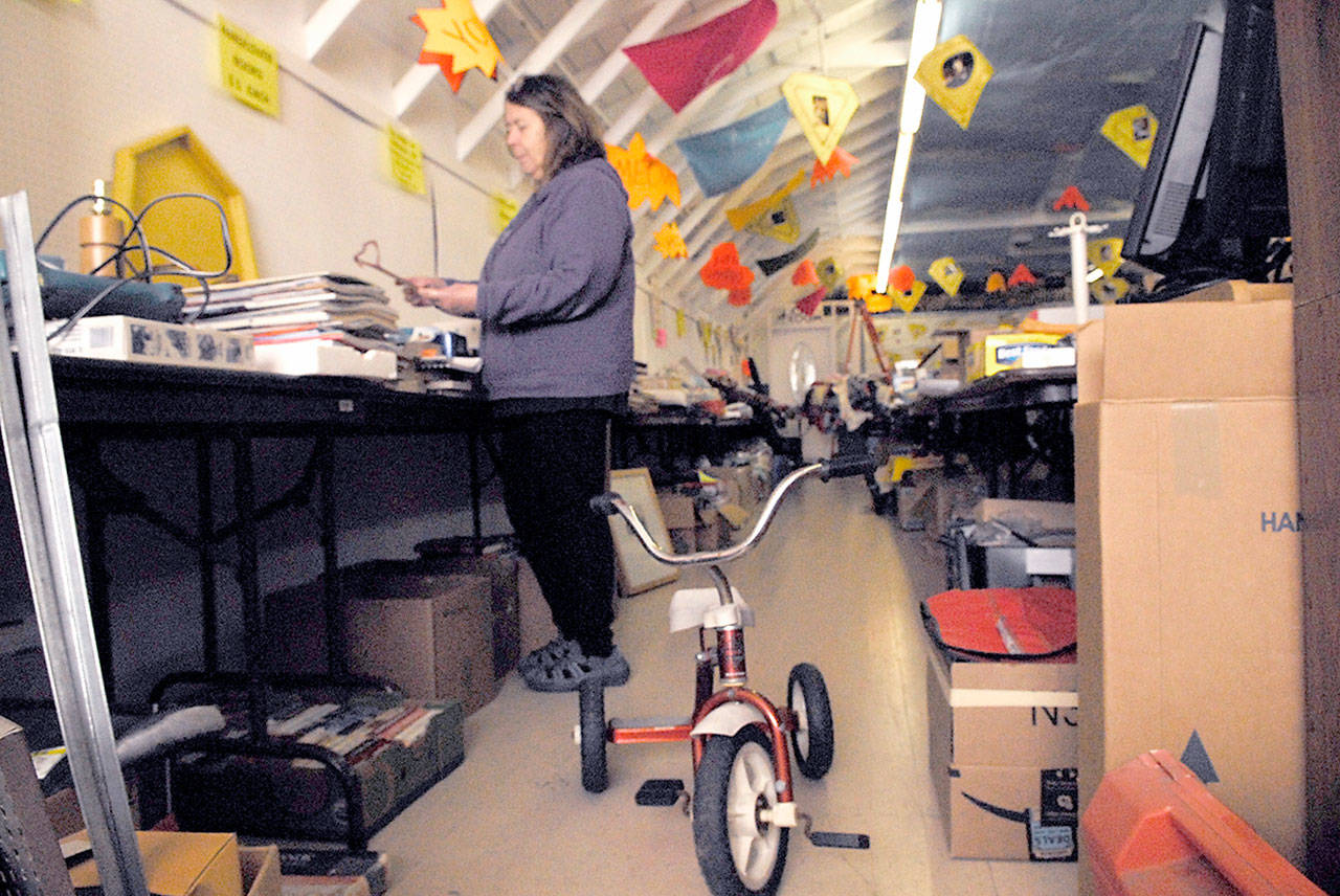 Saturday’s JeffCo Community Garage Sale and Flea Market runs from 9 a.m. to 4 p.m. at the Fairgrounds. The Fair Association’s Sue McIntire inspects some of the donated items. More than 50 different vendors and direct sales companies will participate in the Garage and Flea Market. (Jeannie McMacken/Peninsula Daily News)