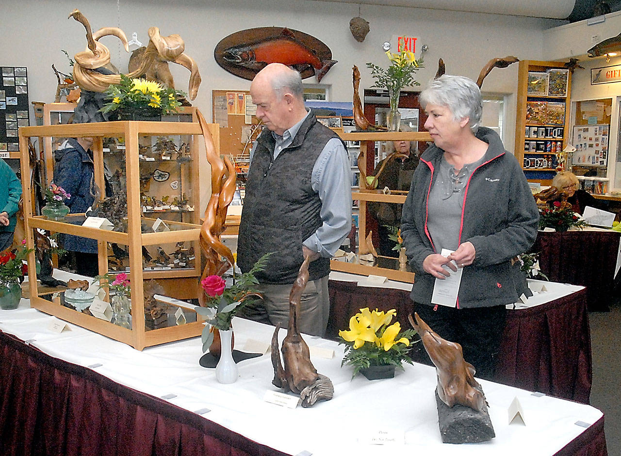 Mark Turley, left, and Jann Hale, both of Sequim, examine a table filled with driftwood sculptures at the Dungeness River Audubon Center at Sequims Railroad Bridge Park during last years Spring Diftwood Art Show. (Keith Thorpe/Peninsula Daily News)