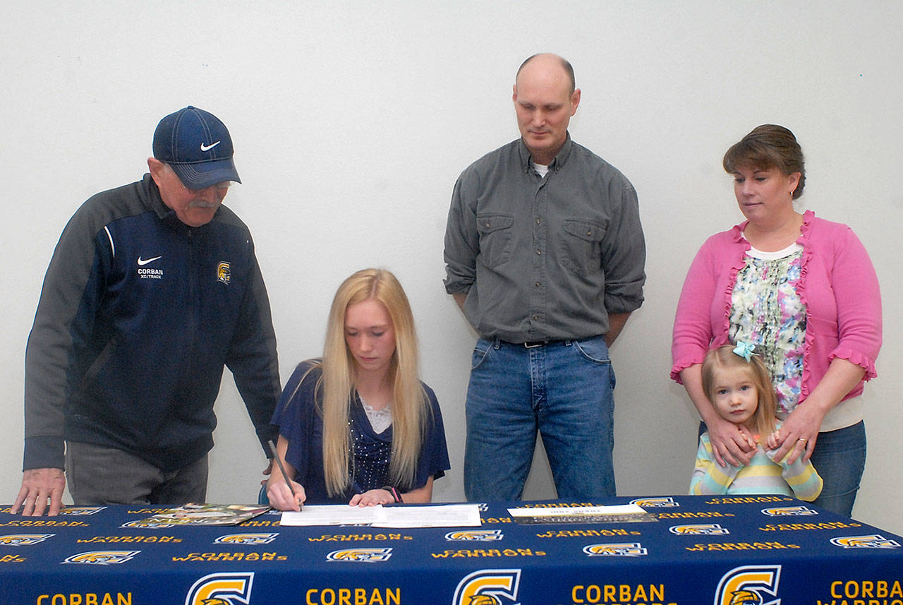 Port Angeles multi-sport athlete Gracie Long, seated, signs a letter of intent to attend Corban University in Salem, Ore., while surrounded by, from left, Corban track and cross-country coach Norm Berney, her parents, Kenton and Alyssa Long, and sister, Tessa Long, 4, on Wednesday at Port Angeles High School.                                Keith Thorpe/Peninsula Daily News