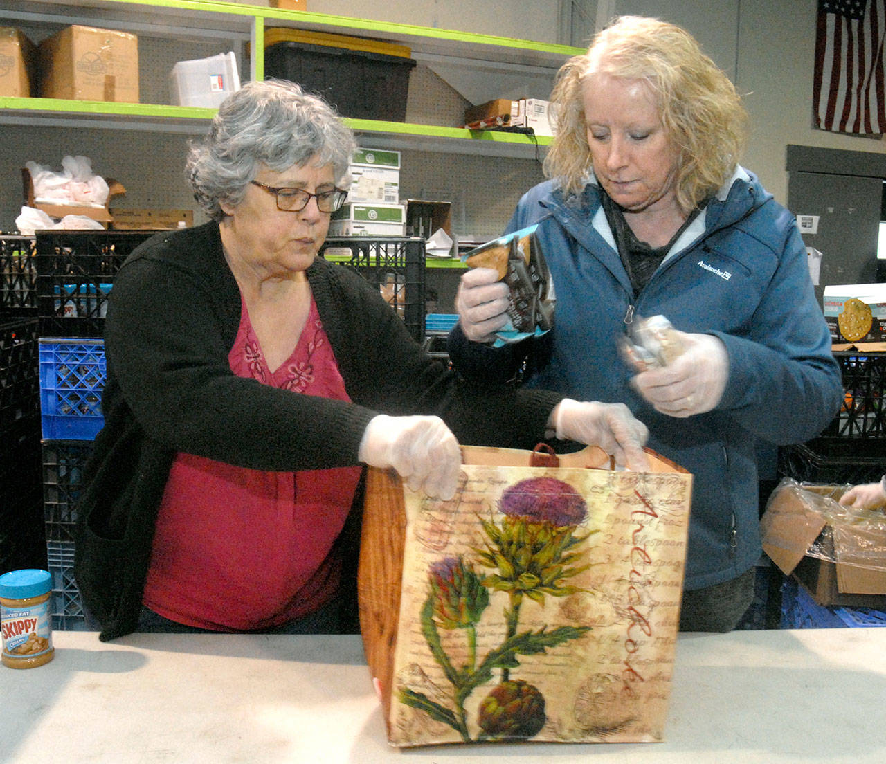 Kiwanis Club members Martha Standley, left, and Carla Sue fill bags of food for needy families at the Port Angeles Food Bank. (Keith Thorpe/Peninsula Daily News)