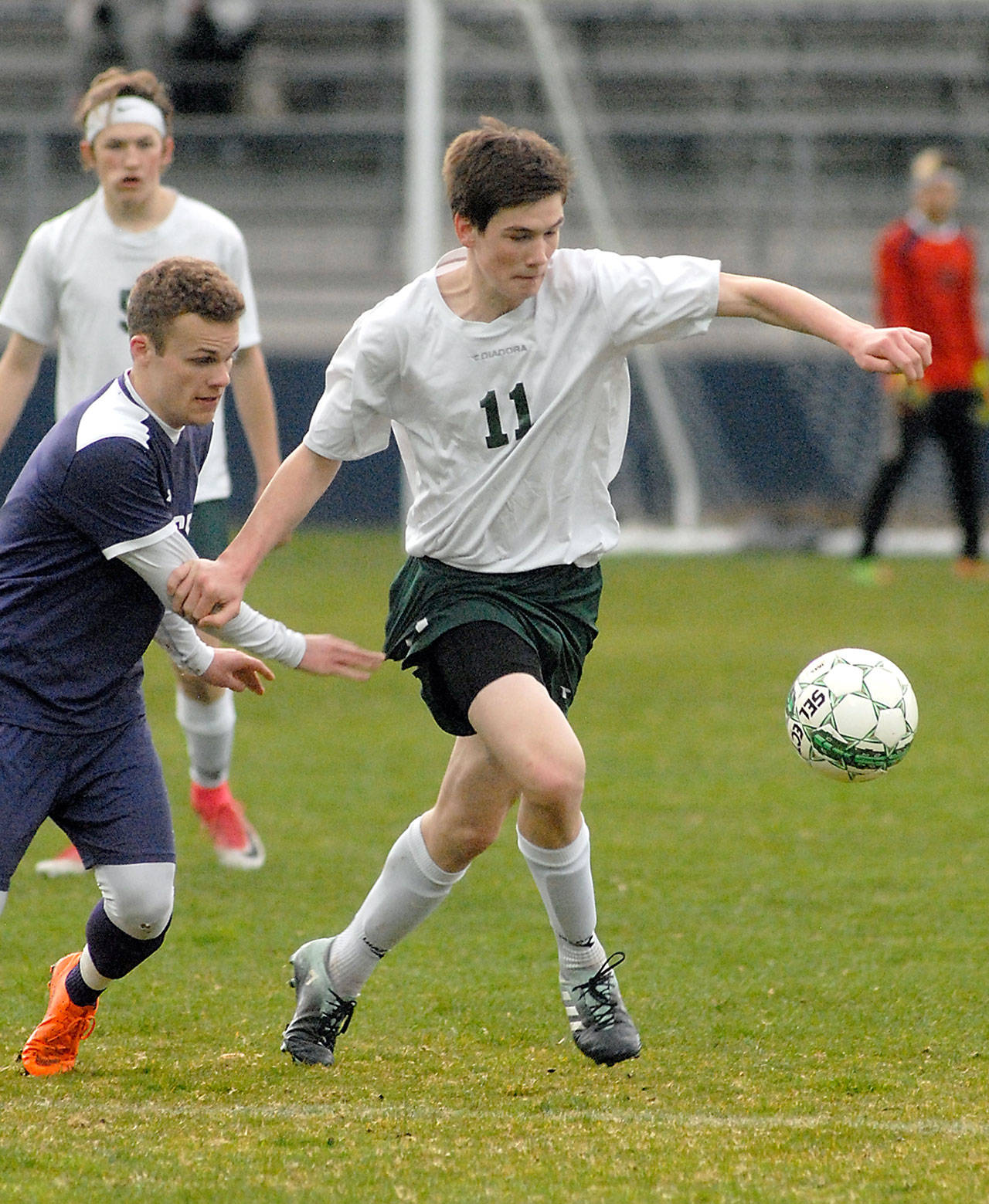 Keith Thorpe/Peninsula Daily News Port Angeles’ Gabriel Long, right, chases down the ball with North Kitsap’s George Beddoe in pursuit during Thursday night’s match at Port Angeles Civic Field. In the background is Port Angeles’ Hollund Bailey.