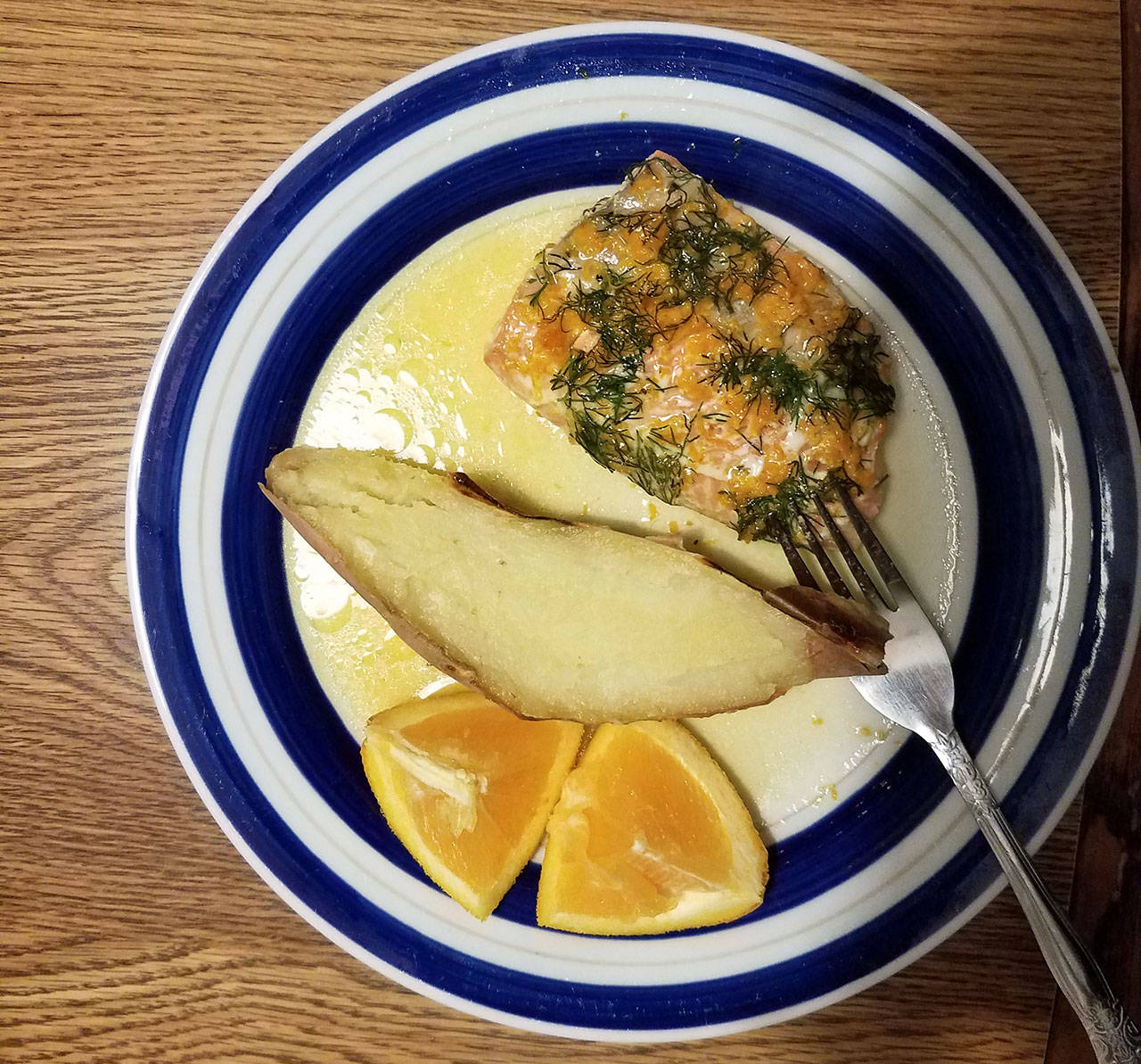 Dill salmon sits ready to eat with half a baked sweet potato and a quarter of an orange. (Emily Hanson/Peninsula Daily News)