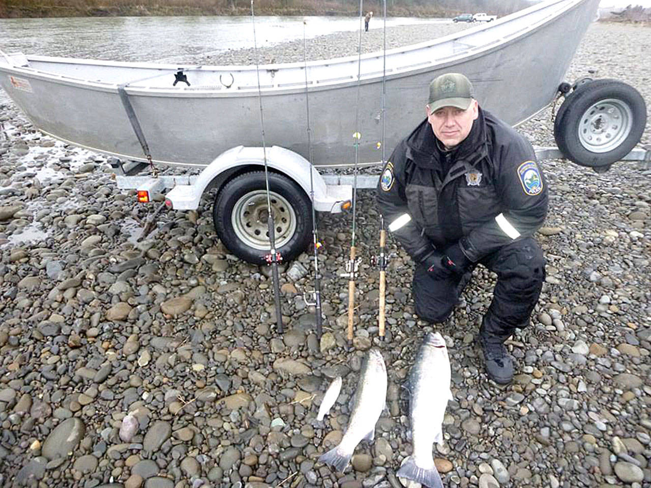 Washington Department of Fish and Wildlife Police Officer Bryan Davidson displays two wild steelhead and an undersized cutthroat trout along with the rods used to poach the fish after a January incident on the Quillayute River near Forks. (Washington Department of Fish and Wildlife Police)