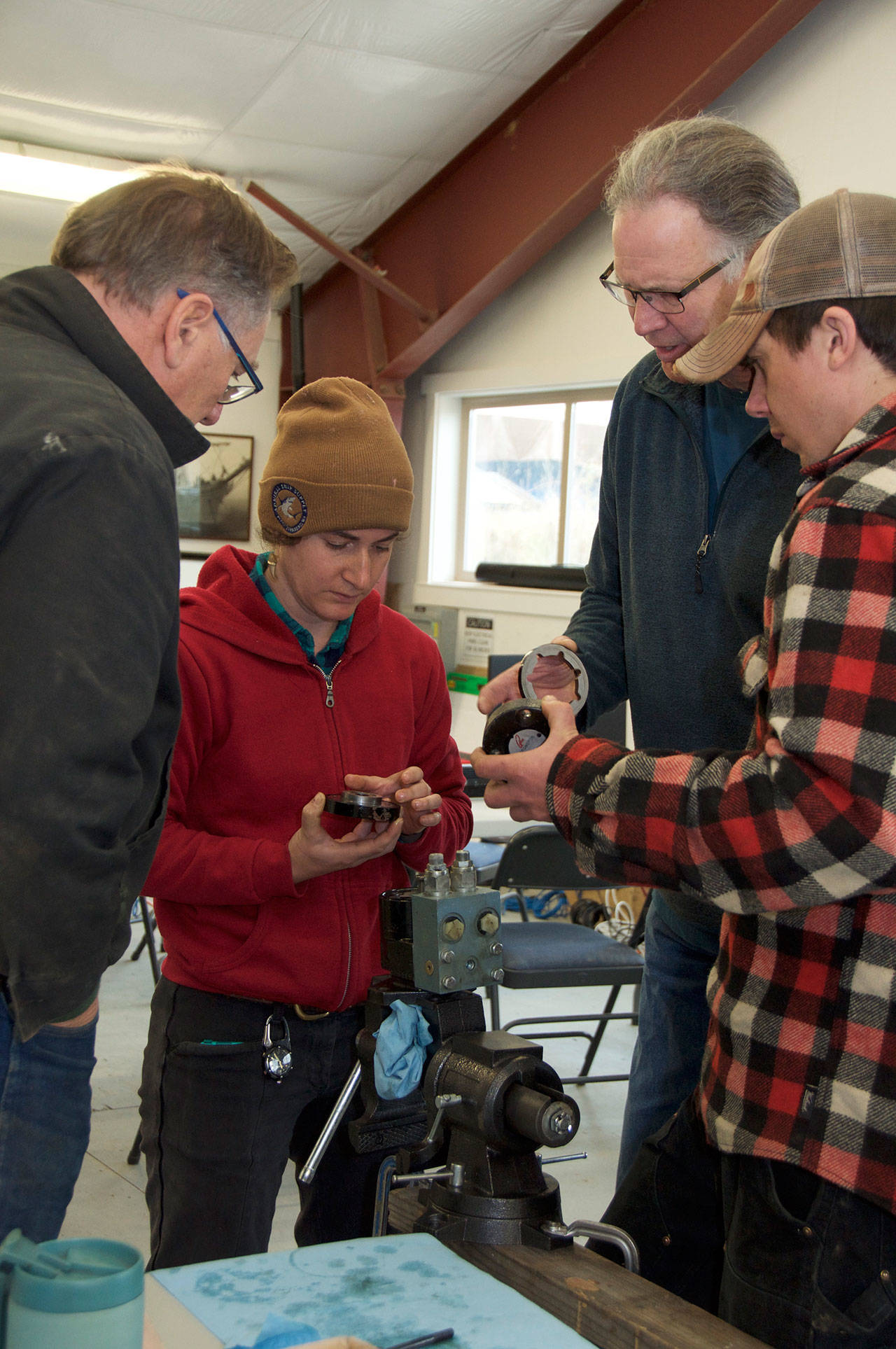 As part of the Marine Hydraulics Intensive at the Northwest School of Wooden Boatbuilding in Port Hadlock, instructor Walt Trisdale looks on as students examine parts of a disassembled hydraulic motor. (Elizabeth Becker)