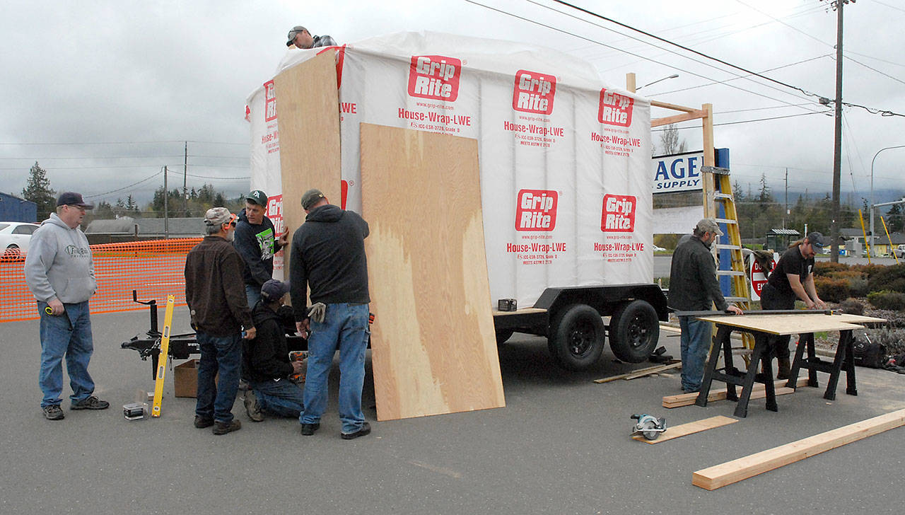 Workers assemble a demonstration tiny home that will be used to promote the Pennies for Quarters organization in its efforts to provide temporary housing for veterans. The home-raising continues from 10 a.m. to 2 p.m. today in the parking lot of Hartnagel Building Supply, 3111 U.S. Highway 101 in Port Angeles. When completed, the home will be used in parades and other public events to raise awareness of homeless veterans and the efforts of Pennies for Quarters. (Keith Thorpe/Peninsula Daily News)