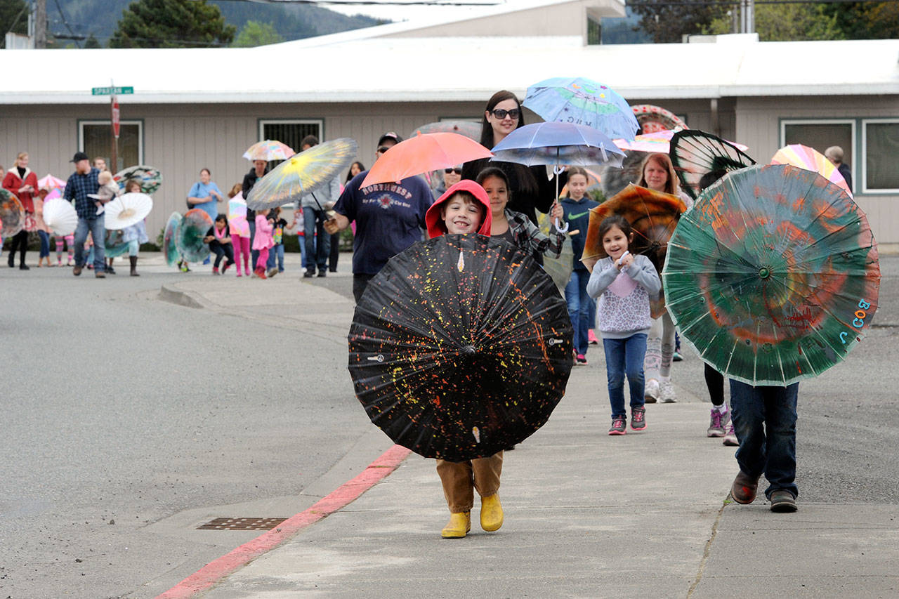 Children accompanied by adults cross Spartan Avenue to go downtown for the 2017 Rainfest Umbrella Parade. About 45 decorated umbrellas were in the parade. (Lonnie Archibald/for Peninsula Daily News)